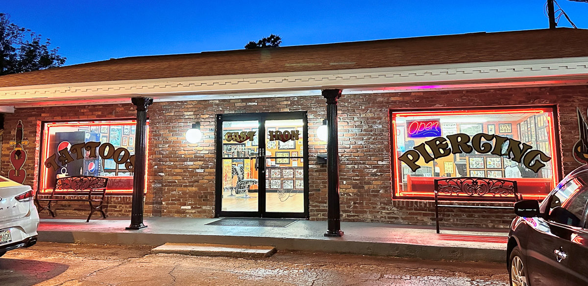 outside cast iron tattoo shop at night with glass windows and red brick walls